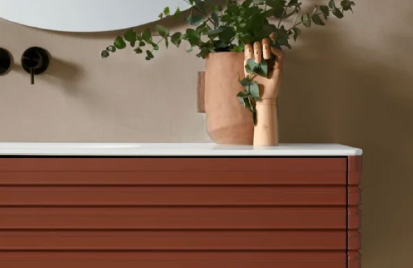 Detalle mueble de baño flotante color marrón. Jarrón decorativo en madera.