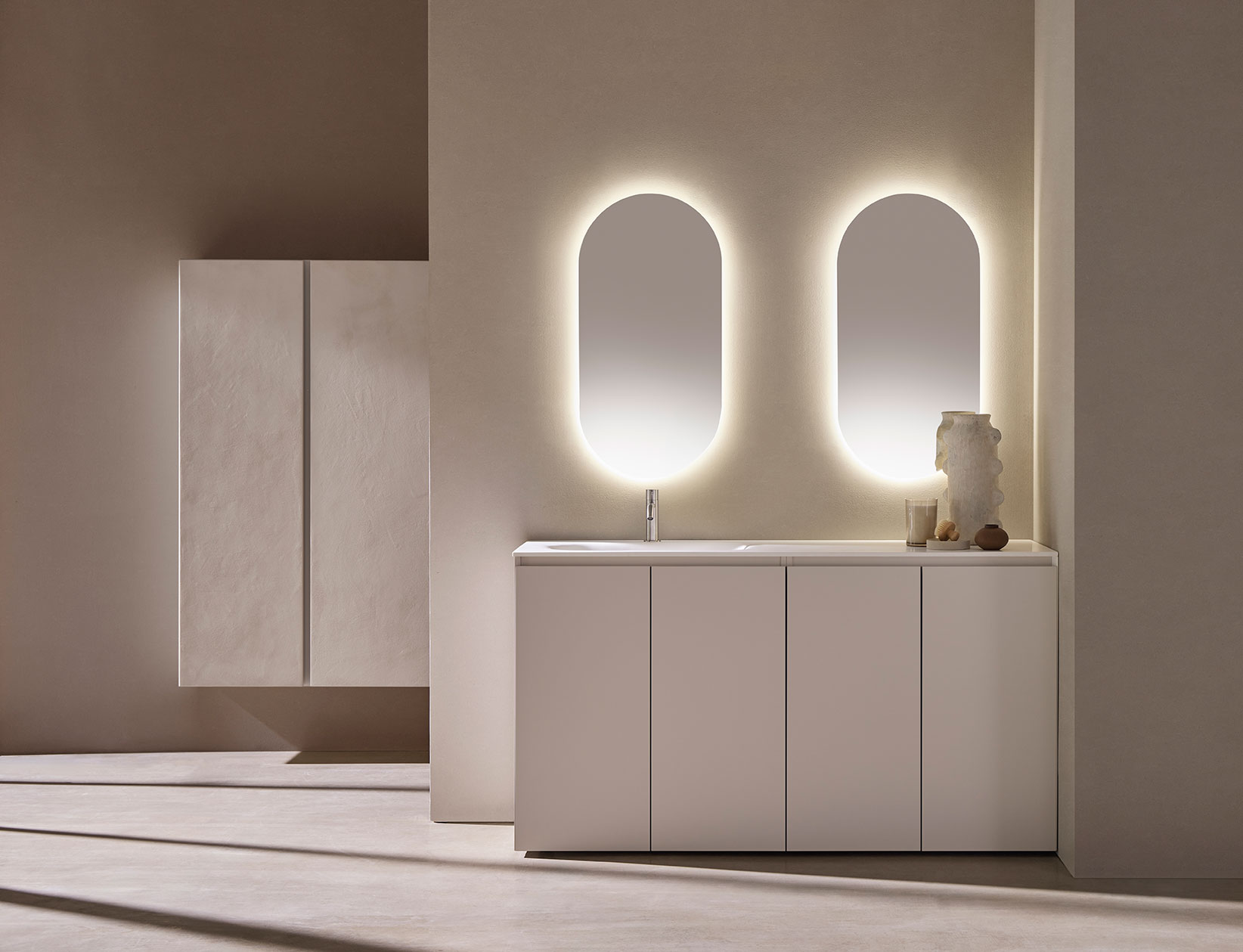 Mueble de baño color blanco con cajones simétricos. Grifería en plata y espejos ovalados.
