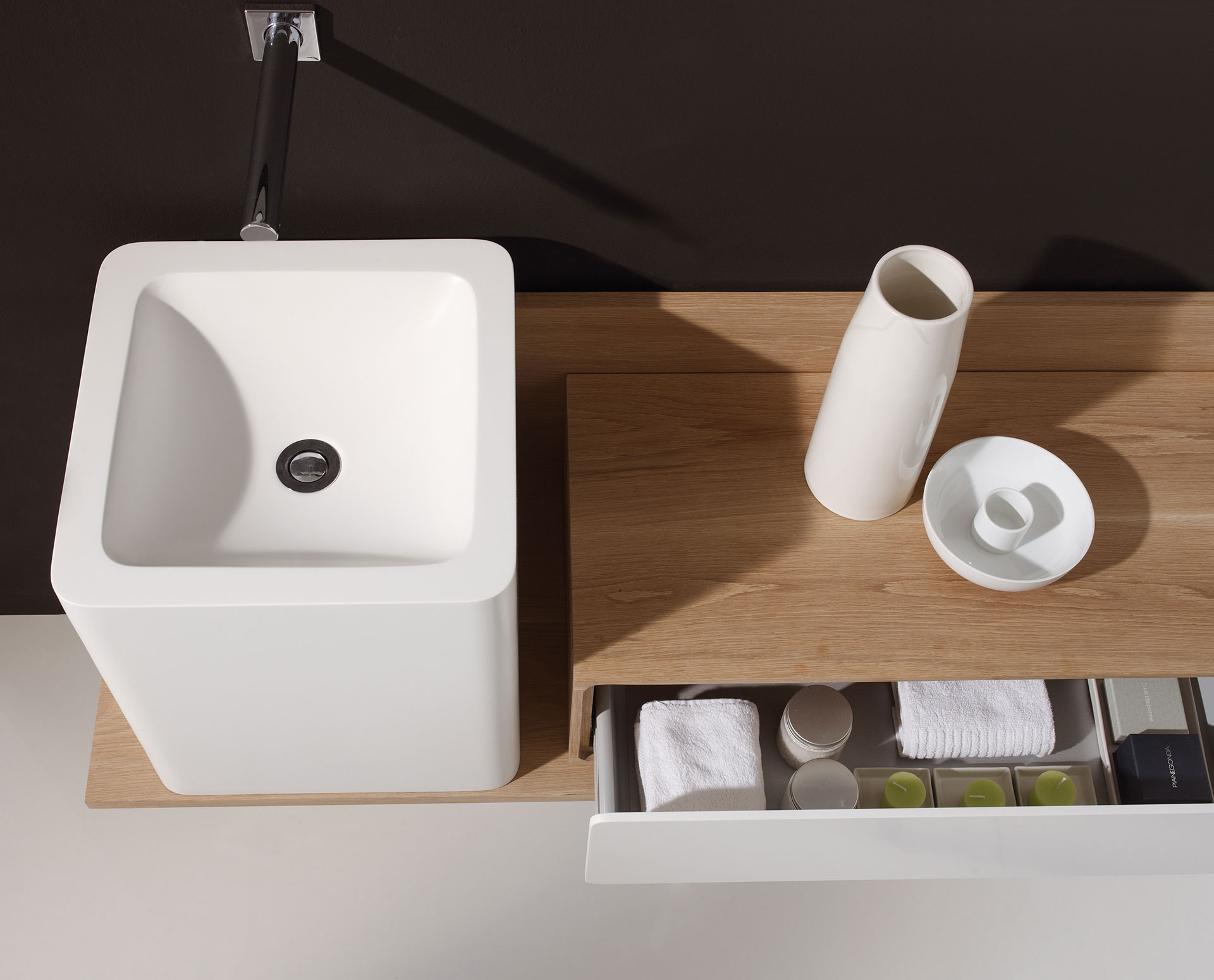 Detalle mueble de baño Puma flotante asimétrico con pilar cuadrangular en blanco y cajon en blanco y madera