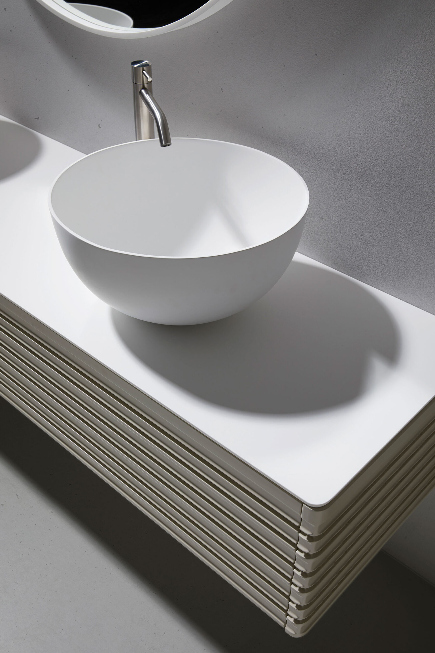 Detalle mueble baño rectangular flotante Rodó con superficie lisa blanca y parte inferior en beige con textura