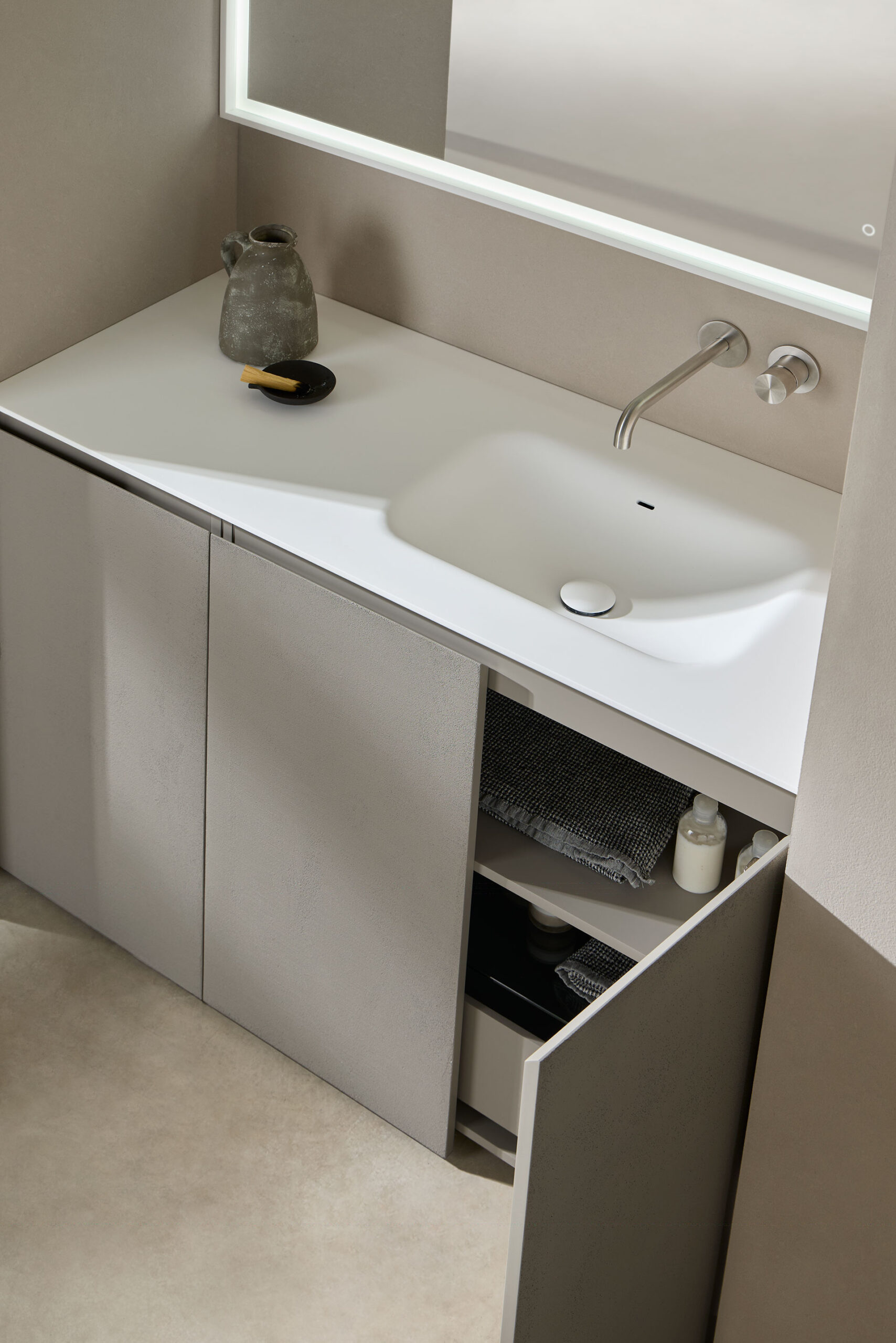 Detalle mueble baño simétrico Nude en color niebla dividido en 3 con baldas en el interior y con superficie en blanco